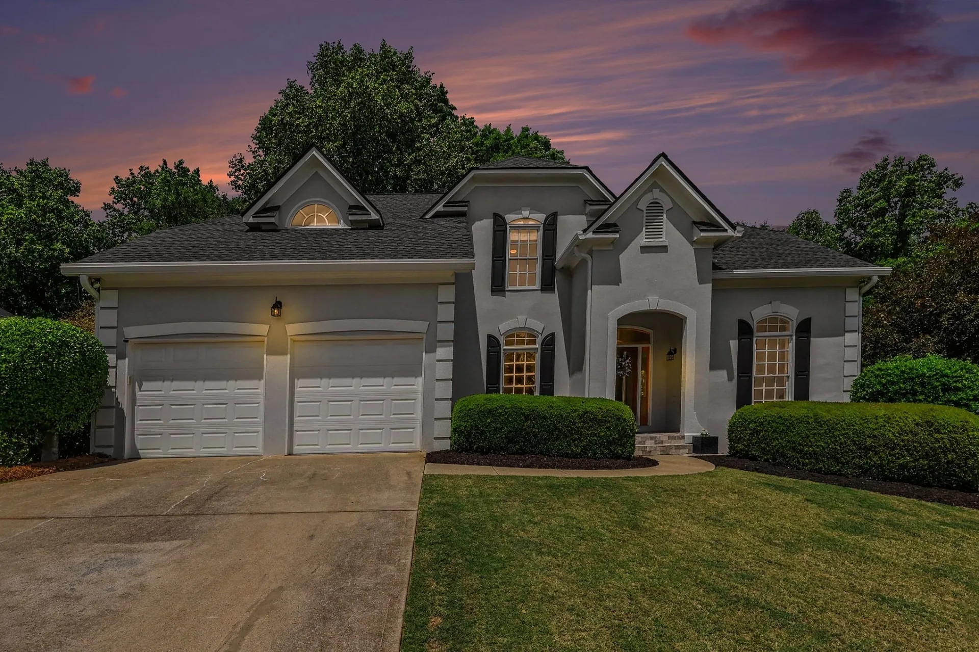 Front elevation of a stucco two-story home Peter sold in Olde Atlanta Club, photographed at dusk